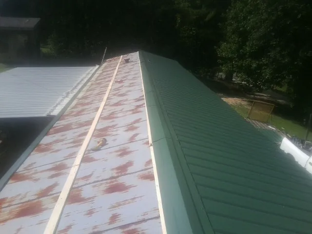 Old rusted panels beside newly installed green metal roofing — Wind Damage Roof Repair by Roofing Brothers in Moonachie