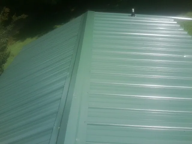 New green metal panels meeting at the ridge of a roof — Flat Roof Repair work by our crew in Moonachie