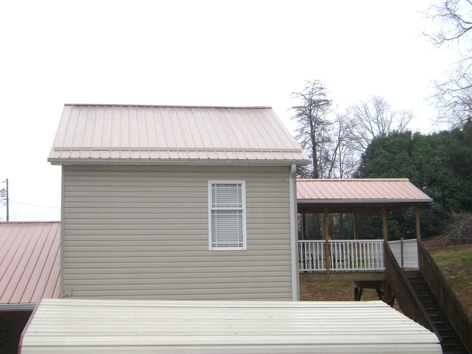 Tan metal roofs on a two story addition and attached porch, from a Roof Replacement job in Moonachie