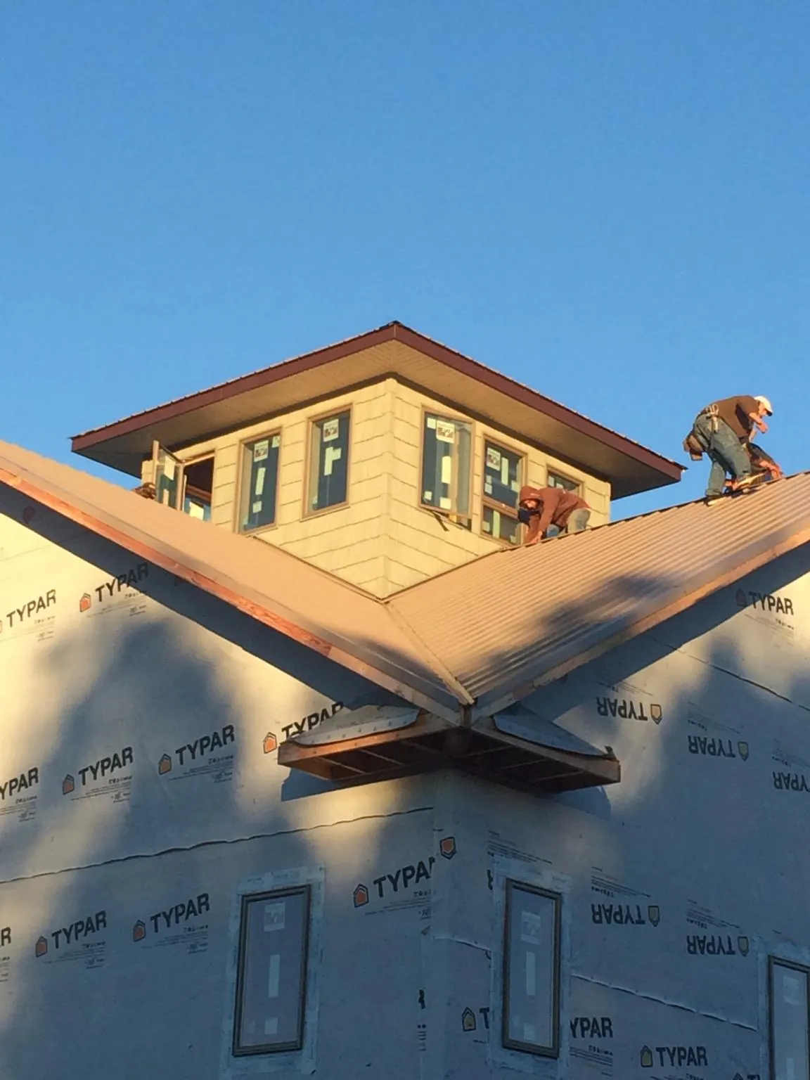 Roofers working around a rooftop cupola on a new metal roof at sunset — Roof Waterproofing in Moonachie by Roofing Brothers
